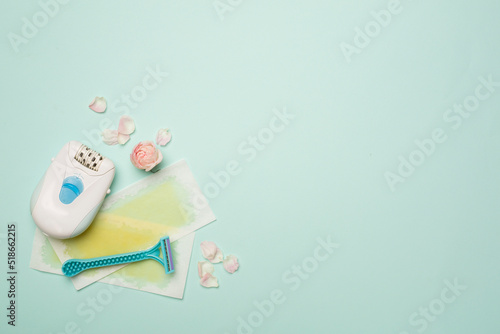 Wax strips, modern epilator and razor with flowers on color background, top view © Liami