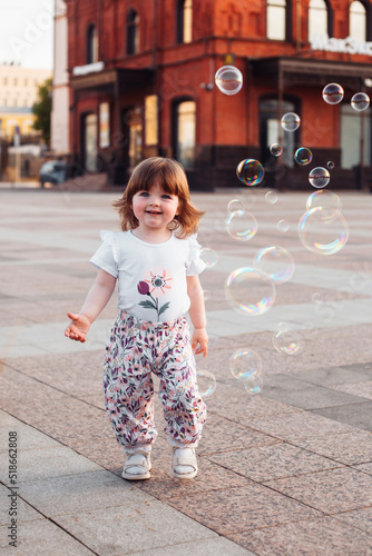 little girl playing on the street with blowing soap bubbles