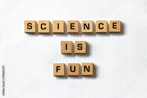 Wooden letters spell out 'science is fun' on a blank white lined notepad. Hardwood desk surface. Back to school, in-person learning, online learning, studying, no people, studies, primary school.