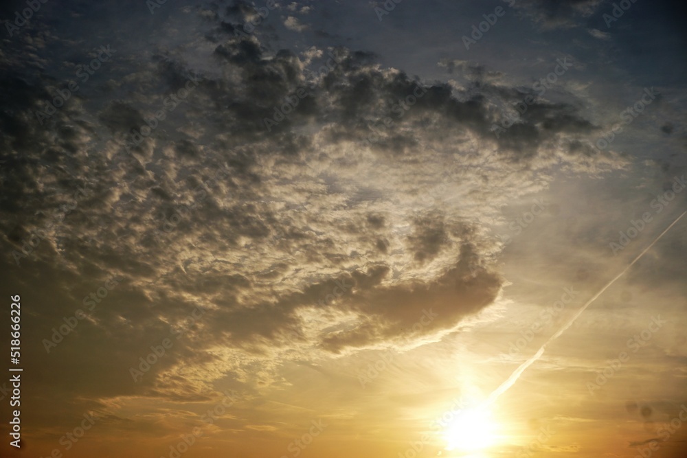Obraz premium Himmel Panorama mit Wolkengebilde und goldgelbe Sonne bei Sonnenuntergang am Abend im Sommer