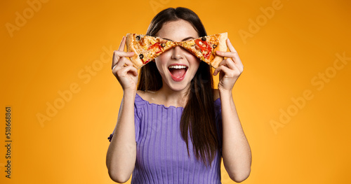 Happy smiling woman holding pizza slices on eyes with excited face expression, concept of pizzeria delivery, food takeout and eating fast food