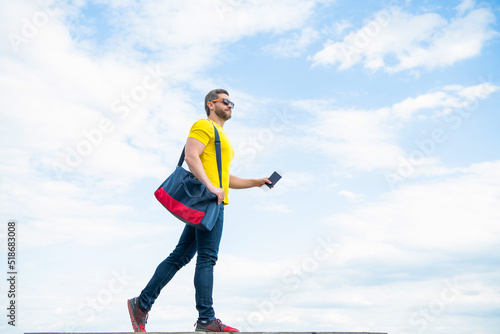 Man traveling on vacation with travel bag and document sky background, copy space