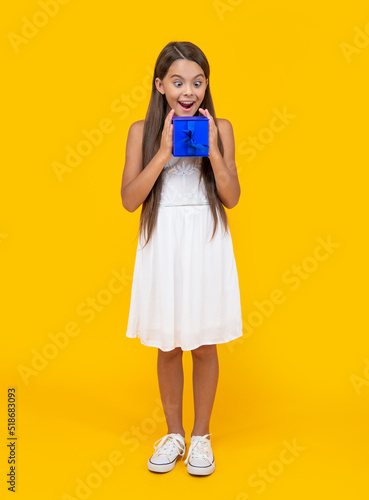 surprised teen kid hold present box on yellow background