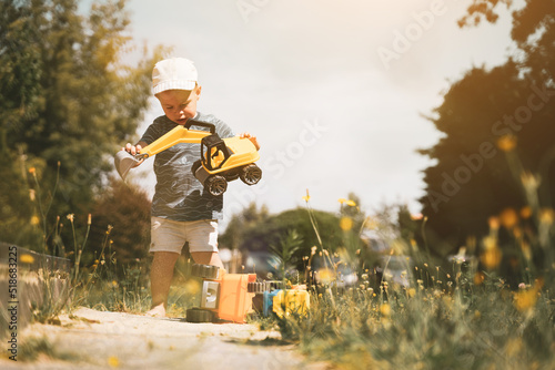 Children playing with toy truck outside. Outdoor creative activities for kids. Summer and childhood concept.