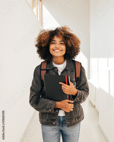 Happy student walking in corridor. Girl in casuals in college.