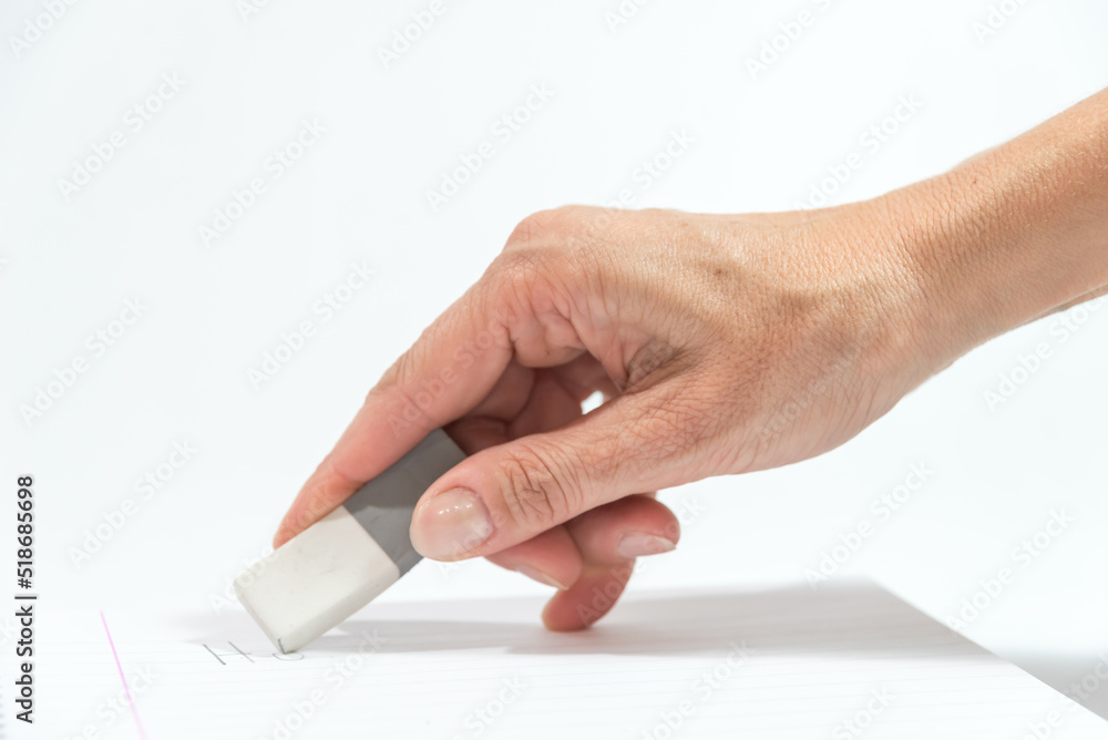 hand holding an eraser over a blank notebook hand holding an eraser over a blank notebook