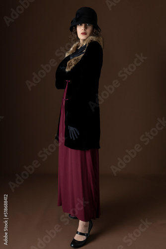 Bild auf Leinwand A 1920s woman wearing a black velvet coat with a fur collar and standing against
