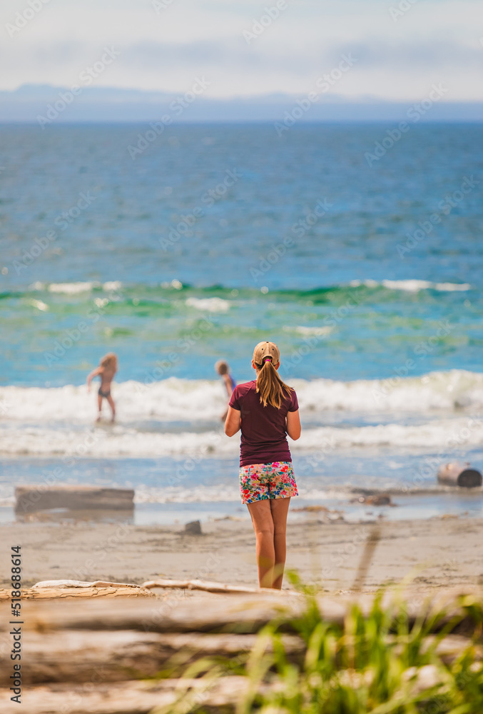 Young girl standing at the beach looking at the ocean in Vancouver Island. Teenager on a summer beach Young girl standing at the beach looking at the ocean in Vancouver Island. Teenager on a summer beach