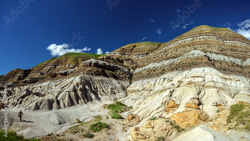 Tourist man walking on a sandstone and photographing the Hoodoos and rock formations in the Canadian Badlands