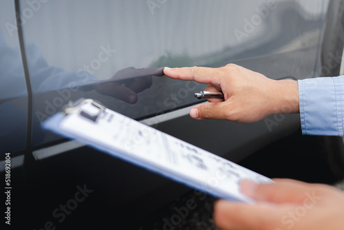 Car insurance Agents examine Damaged Car Inspecting Accident Claim on car paint and body and checklist car body dent point on insurance document for repair work in body paint shop