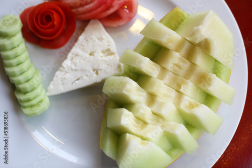 Yellow melon, cucumbers, tomatoes and white cheese in the dinner plate. photo