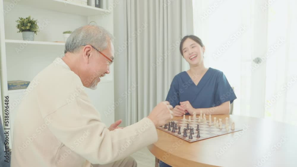 Cheerful Asian nurse, doctor woman assisting old man please and be friend senior elderly man patient playing chess at home Cheerful Asian nurse, doctor woman assisting old man please and be friend senior elderly man patient playing chess at home