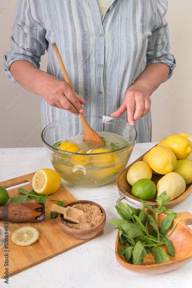Woman's hands preparing homemade lemonade in a glass bowl.