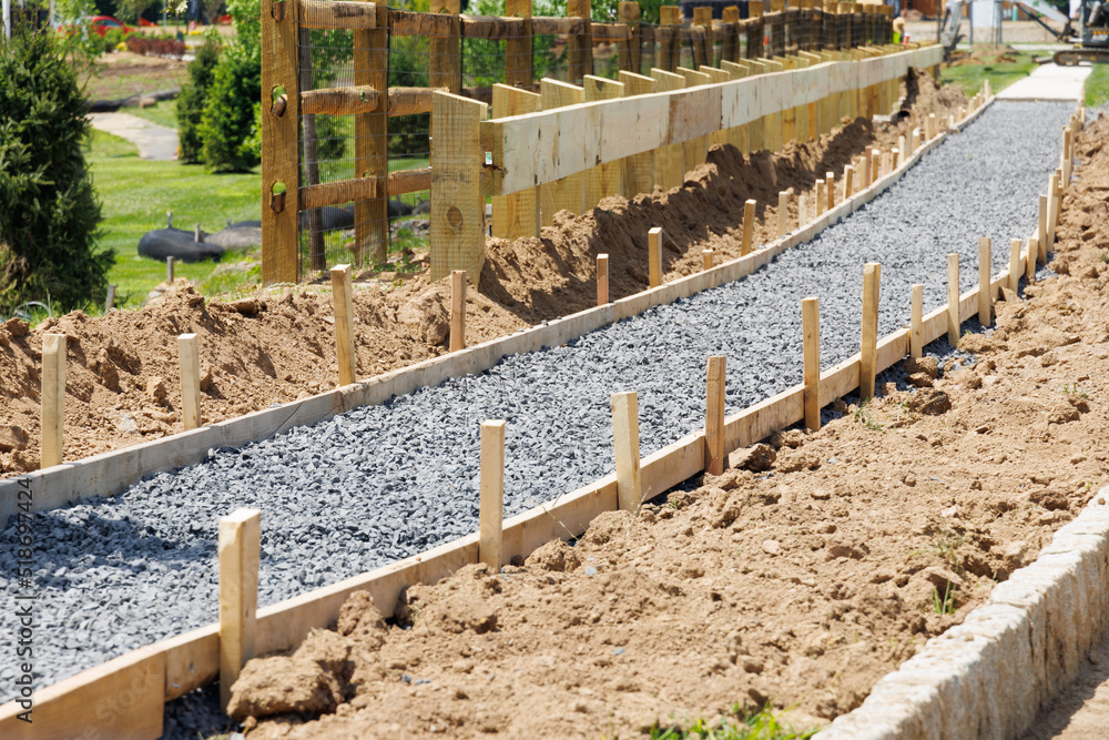 A sidewalk is under construction, a concrete curb is being installed and the foundation of the road is being prepared new gravel sand stone A sidewalk is under construction, a concrete curb is being installed and the foundation of the road is being prepared new gravel sand stone