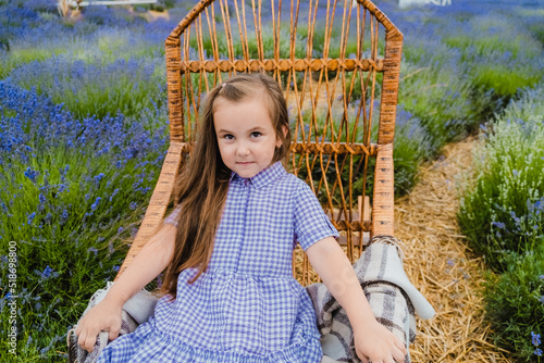 A cool photo session in a field of purple lavender. The child is sitting alone in a wooden rocking chair.