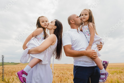 Dad and mom kiss their children in a  field.Family spending time together outdoors. A happy family, mother, father, and son throw up their children daughter.