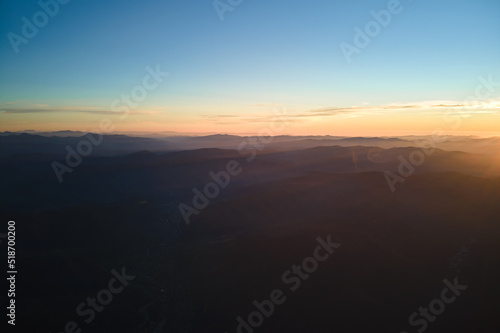 Aerial view of dark mountain hills at sunset. Hazy peaks and misty valleys in evening © bilanol