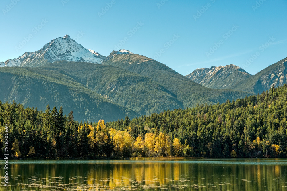 Mountains tower above the autumn foliage at Gun Lake in British Columbia, Canada