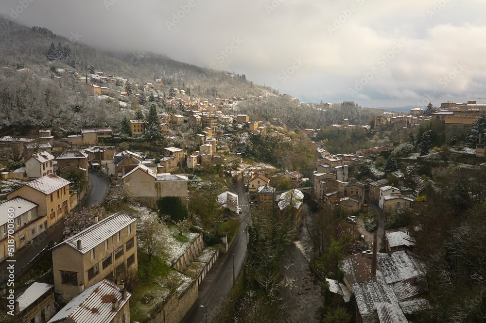 Naklejka premium Aerial winter landscape of dense historic center of Thiers town in Puy-de-Dome department, Auvergne-Rhone-Alpes region in France. Rooftops of old buildings and narrow streets at snowfall