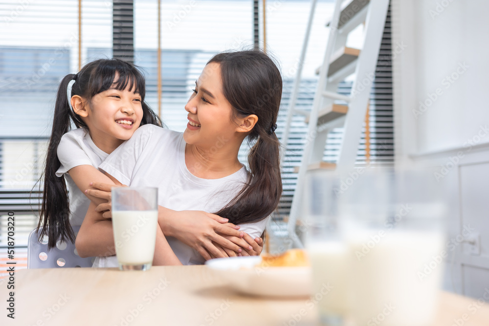 Asian family enjoying breakfast at living room. little girl daughter sitting on table, drinking milk with smiling father and mother in morning. Happy family at home. Asian family enjoying breakfast at living room. little girl daughter sitting on table, drinking milk with smiling father and mother in morning. Happy family at home.
