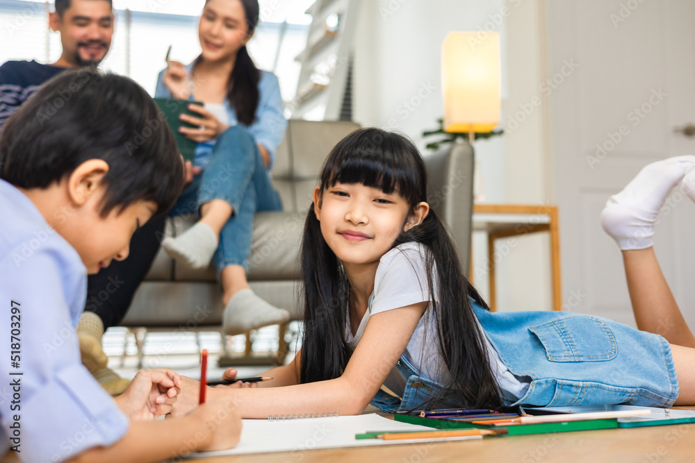 Happy Asian family relaxing on sofa while kid drawing on floor. Little boy girl having fun, friendship between siblings, family leisure time in living room at home. Happy Asian family relaxing on sofa while kid drawing on floor. Little boy girl having fun, friendship between siblings, family leisure time in living room at home.