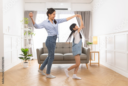 Happy asian family mother father and daughter dancing at home in living room.