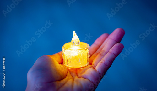 A plastic candle light is placed on the hand. Light from the dark.