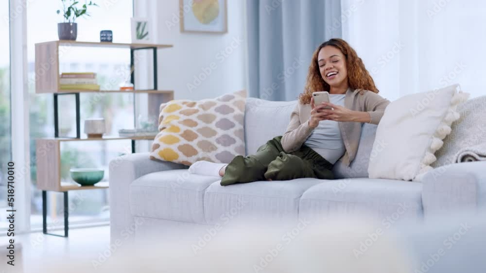 Young woman using mobile to text friends. Teen laughing and texting on phone sitting on couch in lounge. Happy millennial African American teen girl checking social media holding smartphone at home. Young woman using mobile to text friends. Teen laughing and texting on phone sitting on couch in lounge. Happy millennial African American teen girl checking social media holding smartphone at home.
