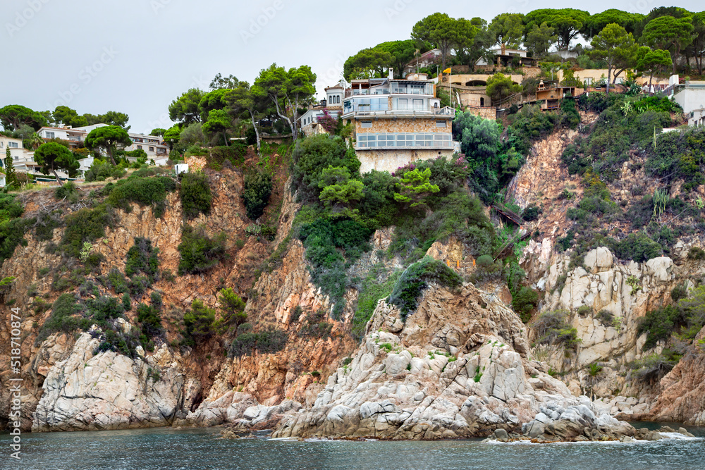 Mediterranean sea with rocky coast with modern buildings on the cliff in Lloret de Mar located in popular Costa Brava, Catalonia, Spain. Amazing rock cliff seascape in the coastline.