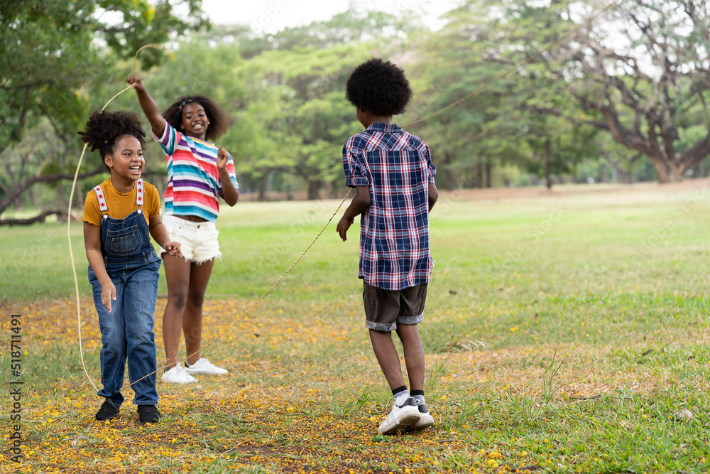 African American children playing jumping over the rope in the park ...