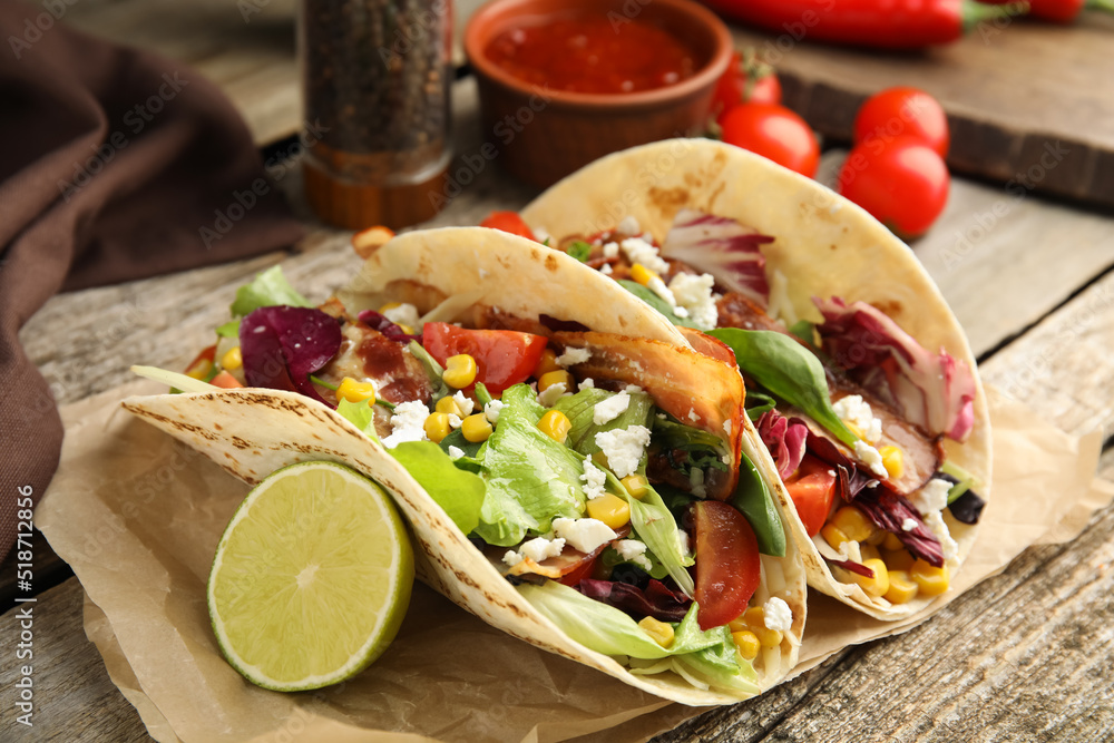 Delicious tacos with fried bacon and lime on wooden table, closeup Delicious tacos with fried bacon and lime on wooden table, closeup