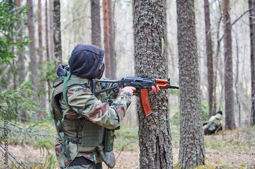 a human in the forest shoots from a machine gun
