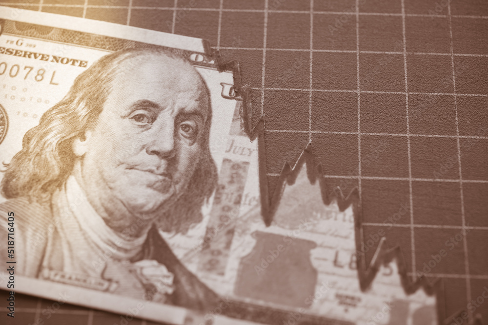 Fototapeta premium Tear off US dollar banknote as chart graph falling down. The Federal Reserve ( FED ) increase % interest rates to fix inflation crisis. World global economy recession and stagflation concept.