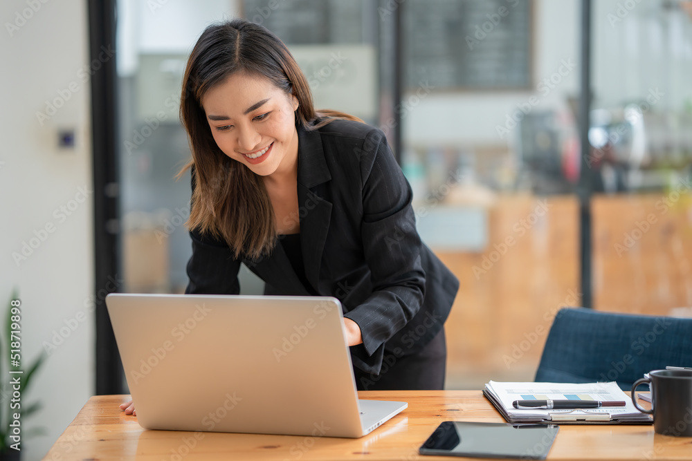 Portrait Female Entrepreneur. Cheerful Asian Businesswoman standing and using a laptop computer.
Portrait Female Entrepreneur. Cheerful Asian Businesswoman standing and using a laptop computer.