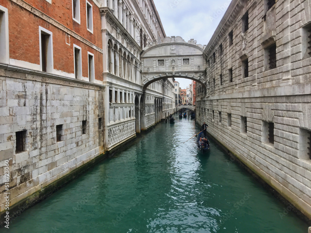 Obraz premium Bridge between two buildings over a canal with gondolas in Venice, Italy