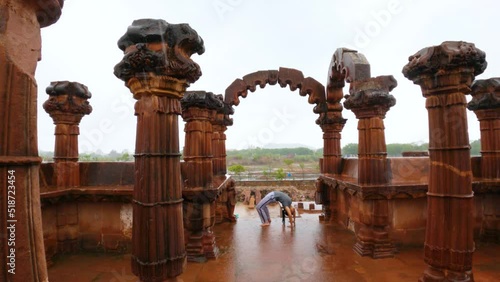 Young Indian woman performing Chakrasana Yoga pose between Pillars of old historic architecture Chhatardi  during rain at Bhuj, Gujarat, India. Bridge pose, Urdhva Dhanurasana also known as Wheel photo