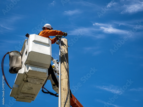 Принти на полотні Power lineman at work in an aerial bucket connecting a new house service on a su