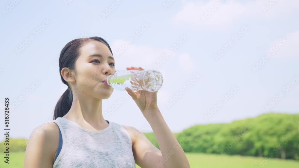 屋外で水を飲む女性　水分補給　熱中症対策