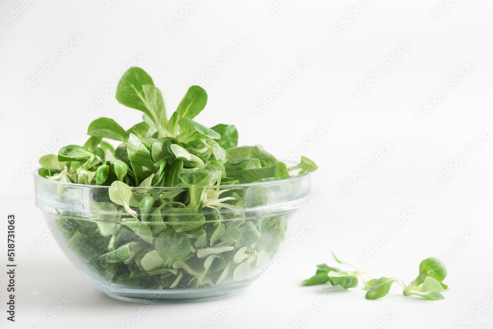 Fresh green salad in transparent glass bowl at white background. Healthy food preparation with lettuce. Front view. Fresh green salad in transparent glass bowl at white background. Healthy food preparation with lettuce. Front view.
