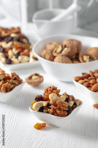 Mix of nuts and raisins on a white wooden table.
