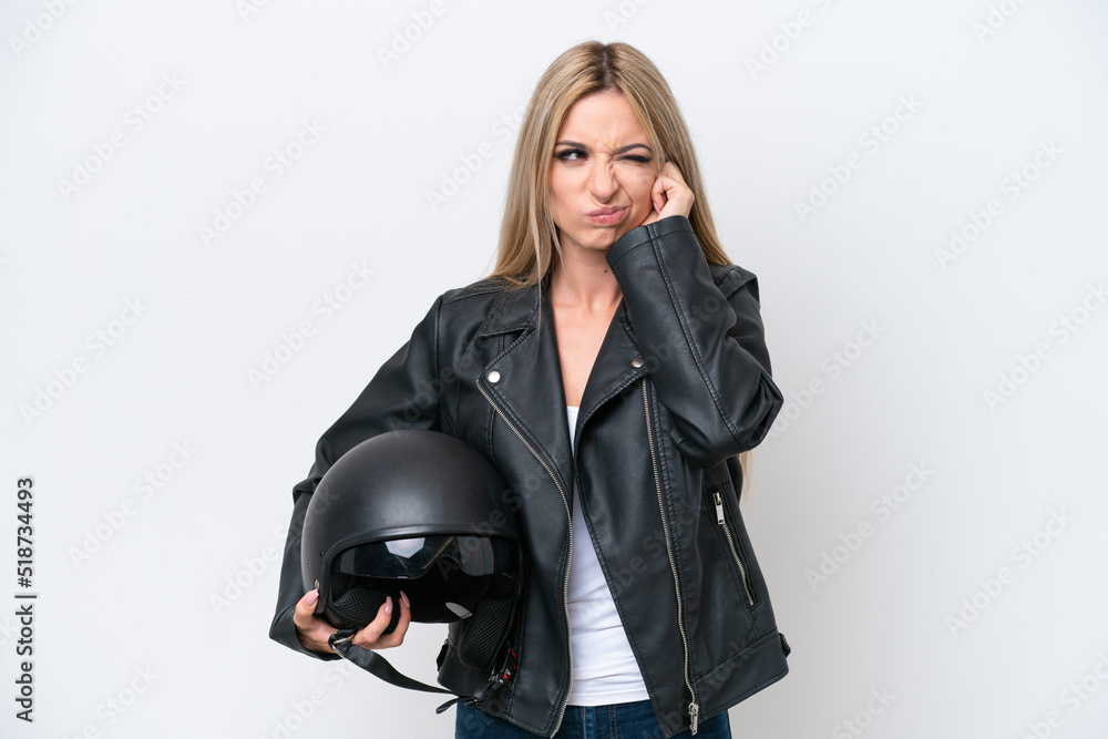 Pretty blonde woman with a motorcycle helmet isolated on white background frustrated and covering ears Pretty blonde woman with a motorcycle helmet isolated on white background frustrated and covering ears
