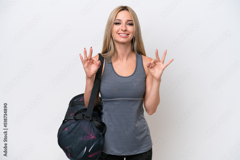 Young sport woman with sport bag isolated on white background showing an ok sign with fingers Young sport woman with sport bag isolated on white background showing an ok sign with fingers