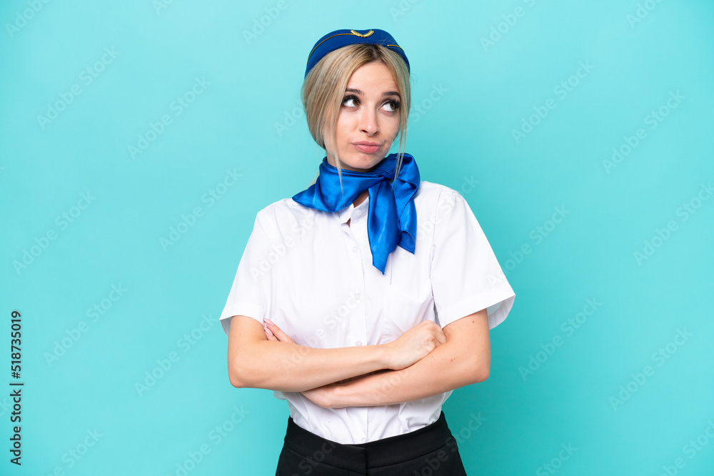 Airplane blonde stewardess woman isolated on blue background making doubts gesture while lifting the shoulders Airplane blonde stewardess woman isolated on blue background making doubts gesture while lifting the shoulders