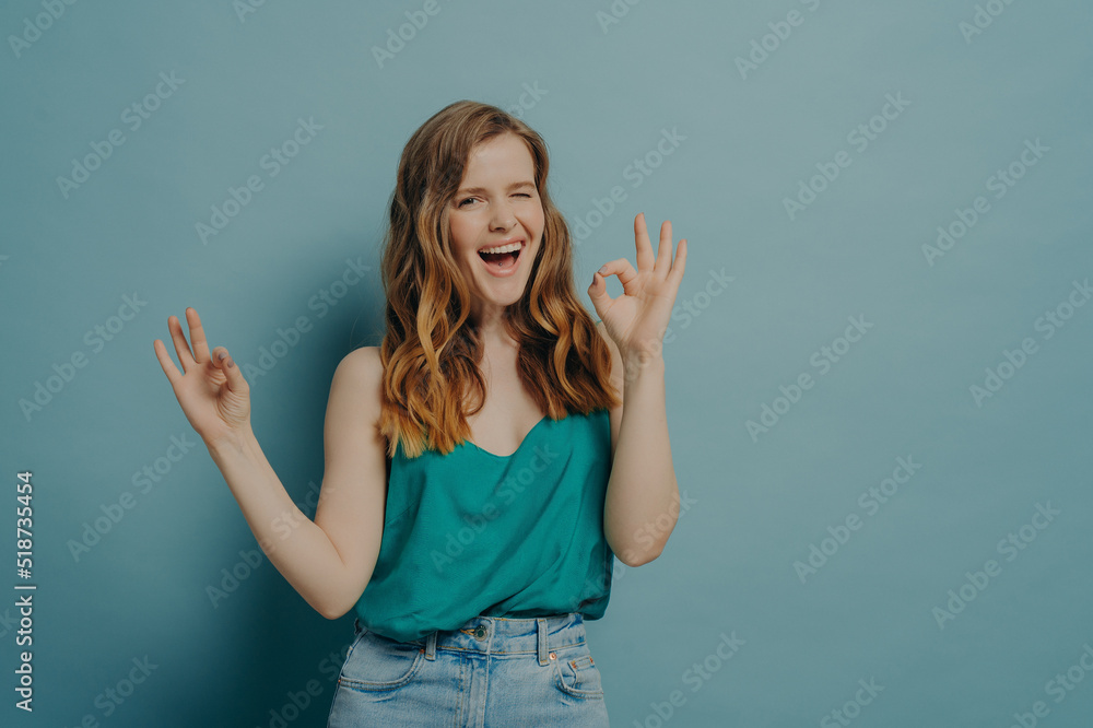 Charming funny girl shows OK sign with hands, winking and looking at camera with big smile Charming funny girl shows OK sign with hands, winking and looking at camera with big smile