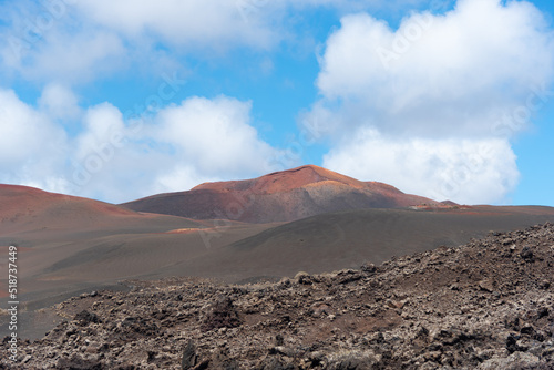 Paisaje desértico y volcánico con un gran volcán inactivo al fondo durante un día soleado de verano en Lanzarote, Islas Canarias.