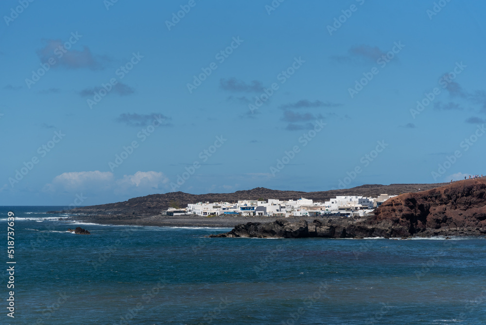 Vista panorámica del pueblo Punta Mujeres con sus tradicionales casas blancas de baja altura frente al mar de aguas cristalinas un día de verano con el cielo azul en Fuerteventura Islas Canarias. Vista panorámica del pueblo Punta Mujeres con sus tradicionales casas blancas de baja altura frente al mar de aguas cristalinas un día de verano con el cielo azul en Fuerteventura Islas Canarias.
