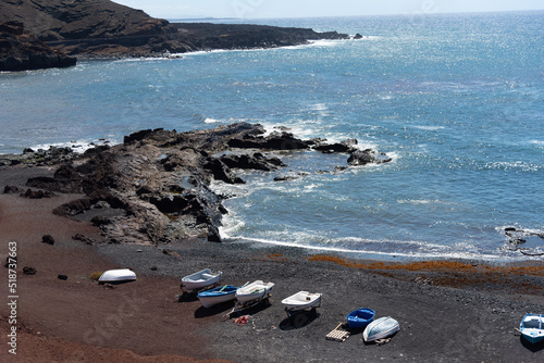 Playa del Golfo en Lanzarote., de arena negra con unas barcas pesqueras azules junto a unos acantilados de roca volcánica al lado del mar turquesa un día soleado de verano Islas Canaria photo