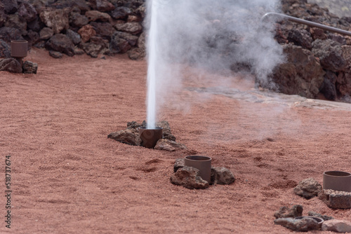 Detalle de un geiser sobre tierra volcánica rodeada de rocas en el Parque Nacional de Timanfaya en Lanzarote Islas Canarias, recursos turísticos y naturales.