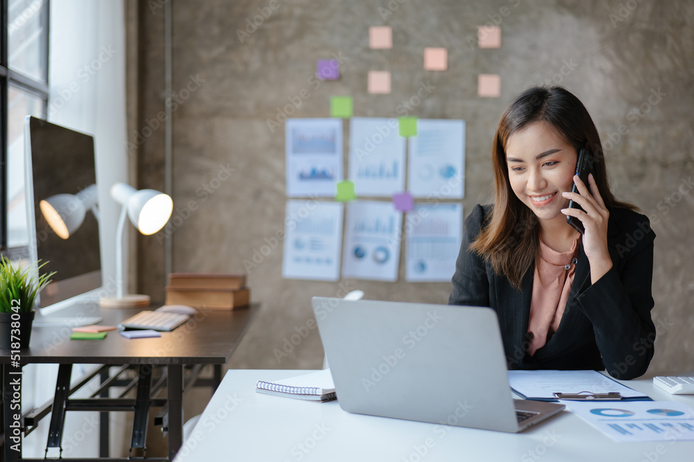 Young business woman discussing and talking with co-worker and client via smartphone and laptop with happy face. Young business woman discussing and talking with co-worker and client via smartphone and laptop with happy face.