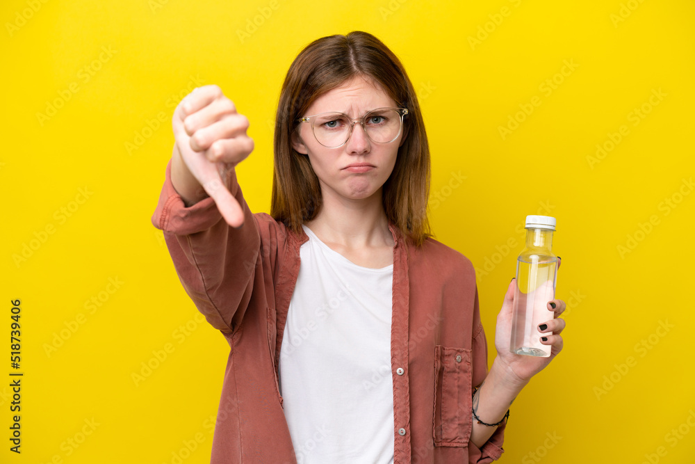 Young English woman with a bottle of water isolated on yellow background showing thumb down with negative expression Young English woman with a bottle of water isolated on yellow background showing thumb down with negative expression
